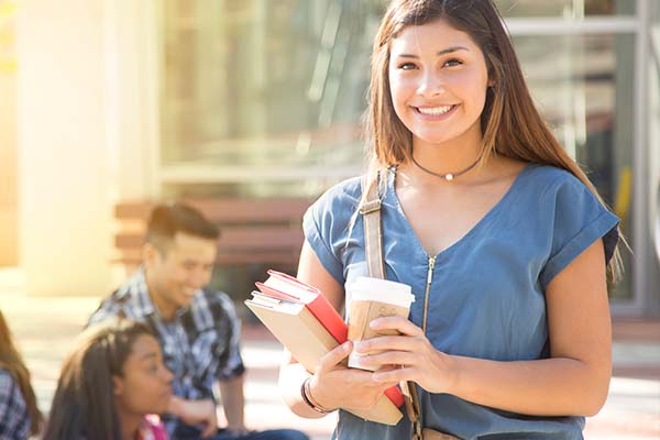Smiling student holding books and coffee